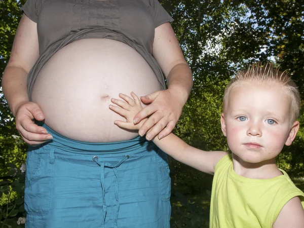 Беременный живот с детской рукой — стоковое фото