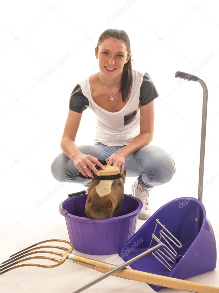 Beautiful girl with horses cleaning equipment