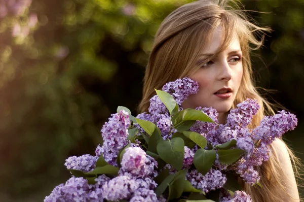 Prachtige blond meisje met lila bloemen in de zonsondergang licht, se — Stockfoto