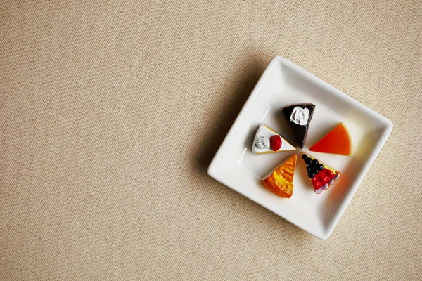 Miniature model of colorful sweets lined up on a white square plate