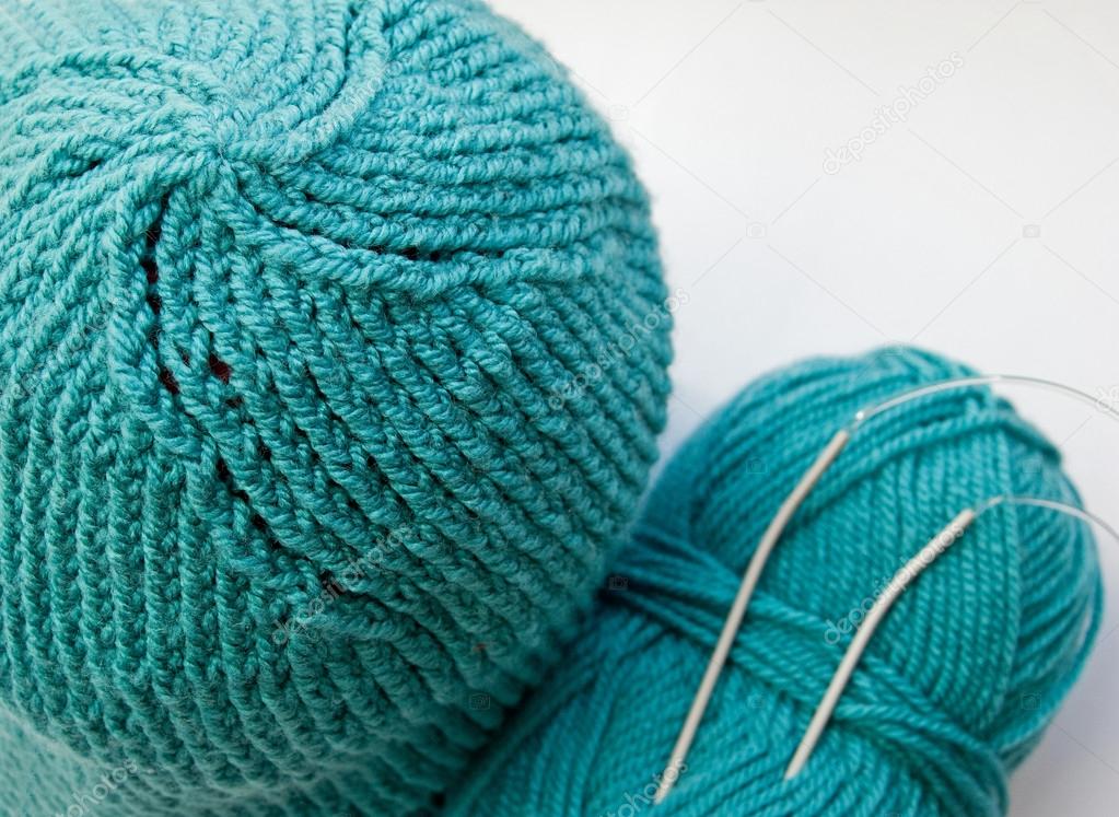 Turquoise knitted hat and wool ball with knitting needles
