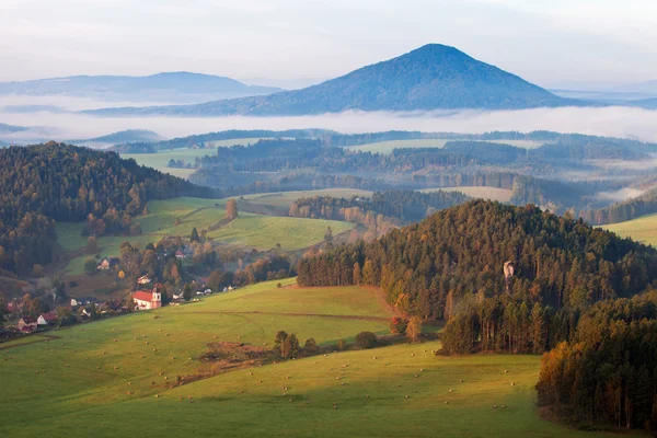 Romantic village at sunset in foggy woodland — Stock Photo, Image