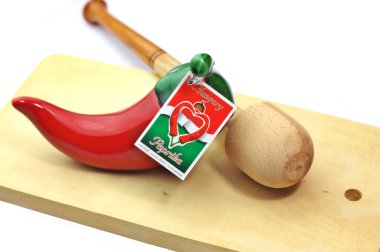 Kitchen composition including an original Hungarian ceramic sweet paprika jar, wooden spice crusher on a wooden cutting board isolated on white