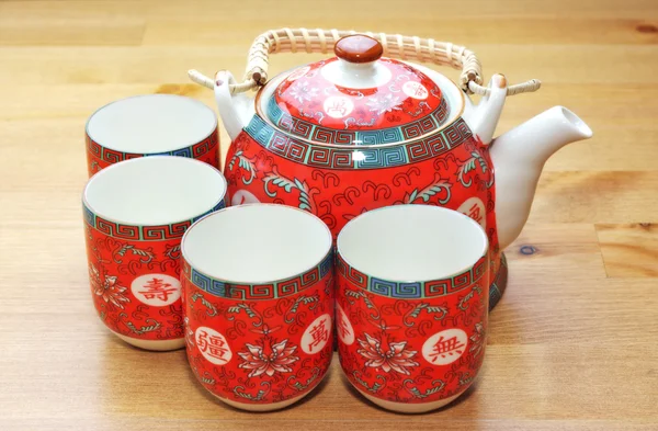 Um conjunto vermelho de bule e xícaras de chá na mesa de madeira — Fotografia de Stock