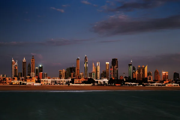 Dubai skyline al atardecer visto desde la costa del Golfo — Foto de Stock