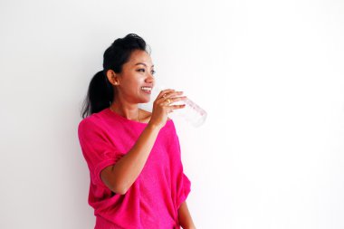 bir şişe su beyaz duvara gülümseyen genç bir kadın