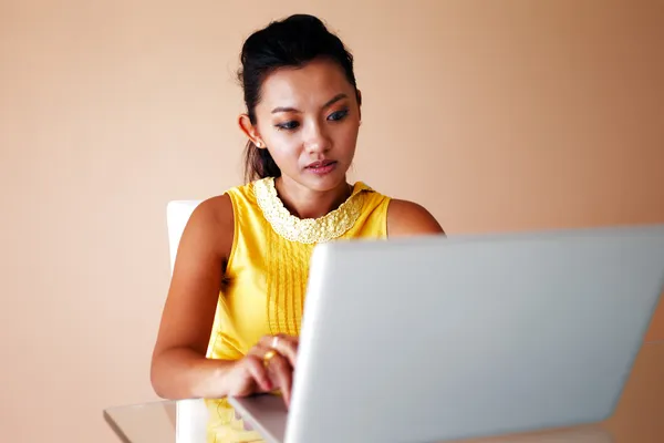Giovane donna in un top giallo con un computer portatile — Foto Stock