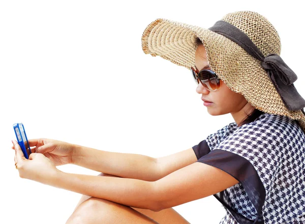 Young woman in a hat and sunglasses using her mobile phone — Stock Photo, Image