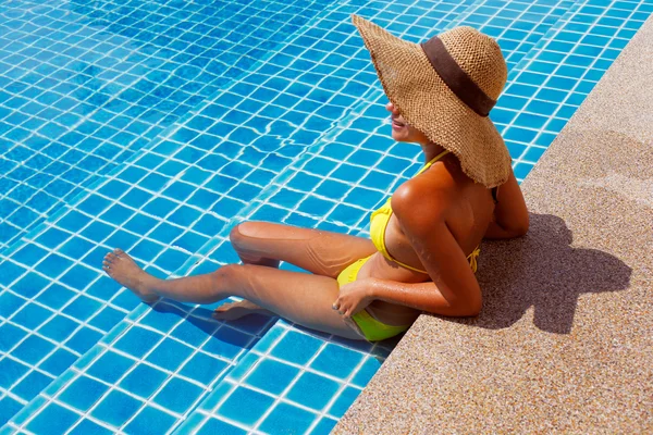 Jovem mulher de fato de banho amarelo em pé numa piscina — Fotografia de Stock