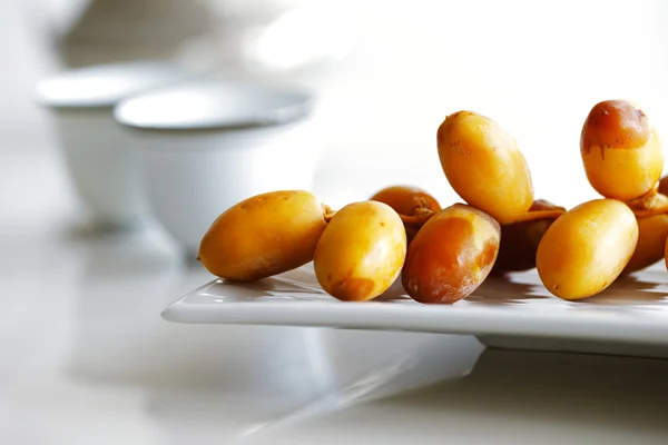 Arabische Datteln auf weißem Teller mit arabischen Kaffeetassen — Stockfoto