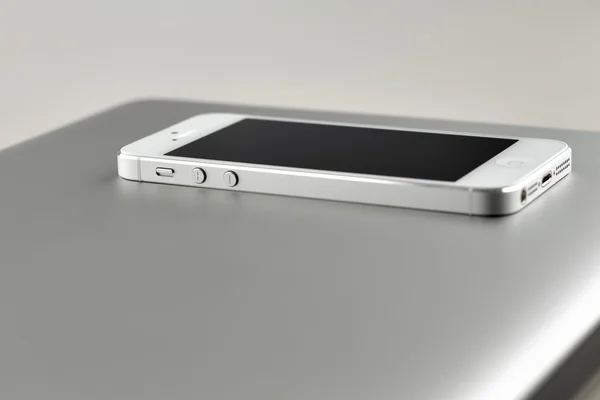 Современный белый смартфон, лежащий на ноутбуке — стоковое фото