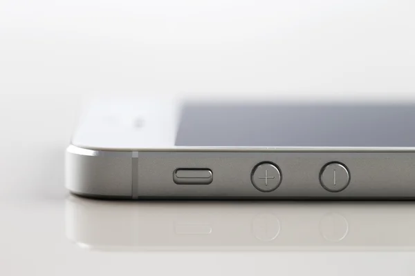 Um novo smartphone branco em um fundo reflexivo branco — Fotografia de Stock
