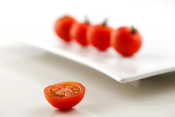 Verse biologische tomaten en een helft van tomaat op de voorgrond — Stockfoto