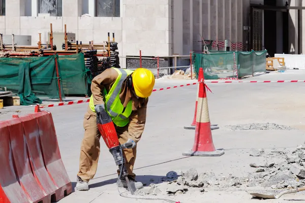 bir işçi bir beton kaldırım kadar kırmak için matkap kullanır.