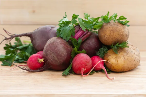 Beets, potatoes, radishes and herbs on a wooden background — Stock Photo, Image
