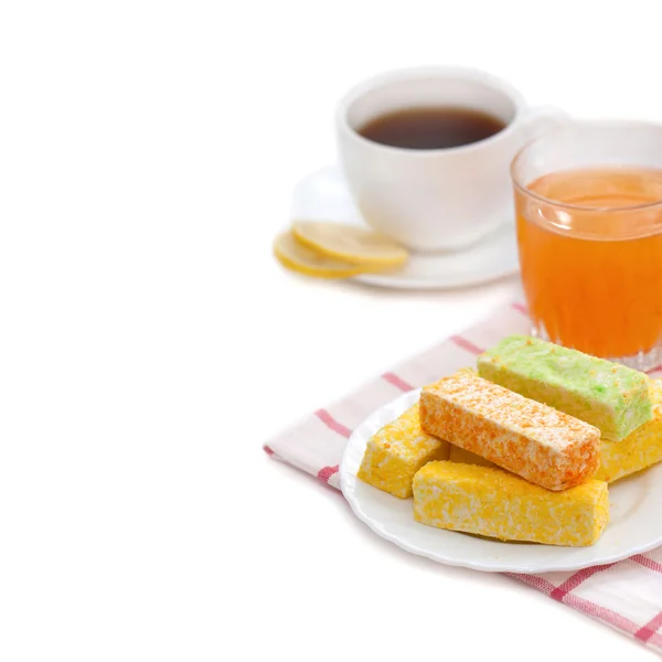 Wielobarwne słodycze, herbata z cytryną, morelowy sok na białym tle — Zdjęcie stockowe