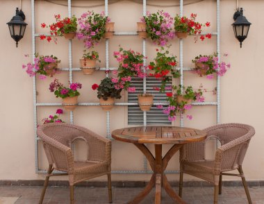 Wicker chairs and a table on the terrace with flowers