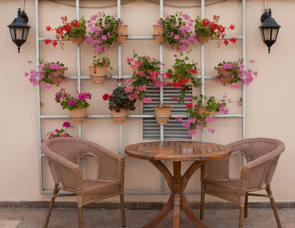 Proutěné židle a stůl na terase s květinami — Stock fotografie