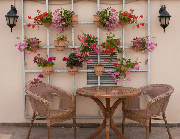 Sillas de mimbre y una mesa en la terraza con flores Imagen De Stock