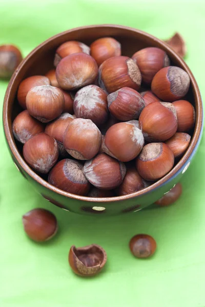 Орехи в деревянной чаше на зеленом фоне — стоковое фото