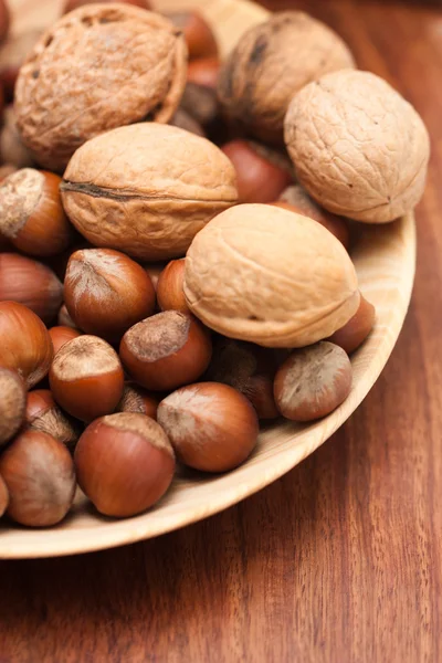 Noten in een houten kom op een bruine achtergrond — Stockfoto