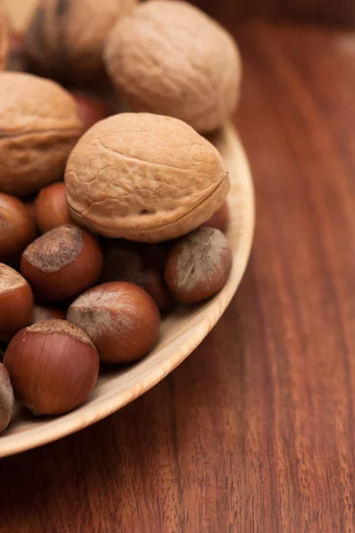 Noten in een houten kom op een bruine achtergrond — Stockfoto