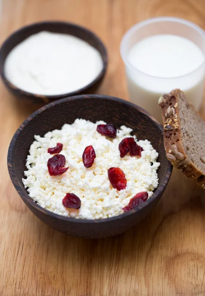 Milk, sour cream, cottage cheese with cranberries and whole grain bread on a wooden table — Stock Photo, Image