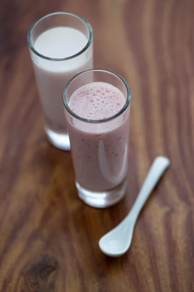 A glass of strawberry smoothie on a wooden background — Stock Photo, Image