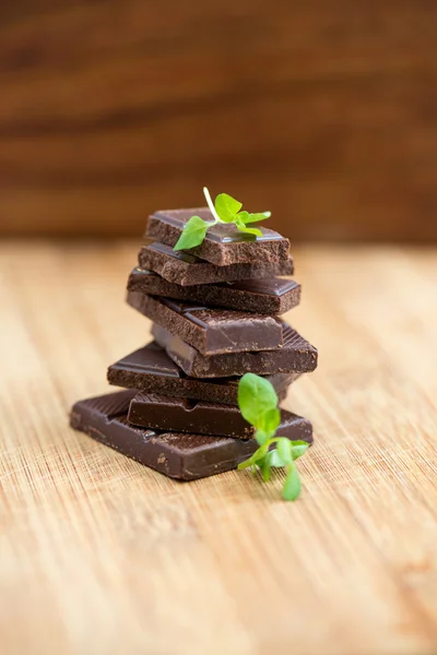 Dark chocolate with fresh mint leaves on wooden background — Stock Photo, Image