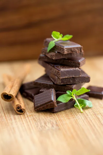 Chocolate escuro, hortelã fresca e canela em fundo de madeira — Fotografia de Stock