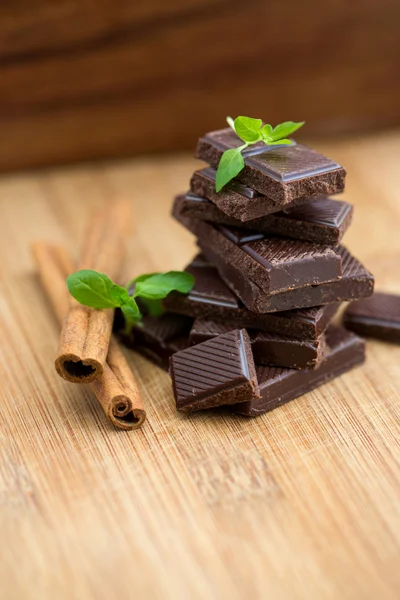 Dark chocolate, fresh mint and cinnamon on wooden background — Stock Photo, Image