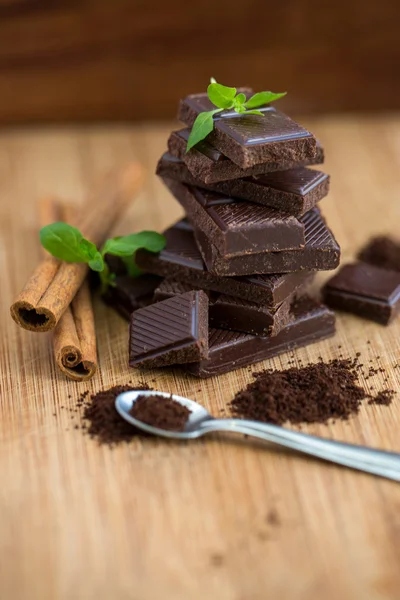 Dark chocolate, fresh mint and cinnamon on wooden background — Stock Photo, Image