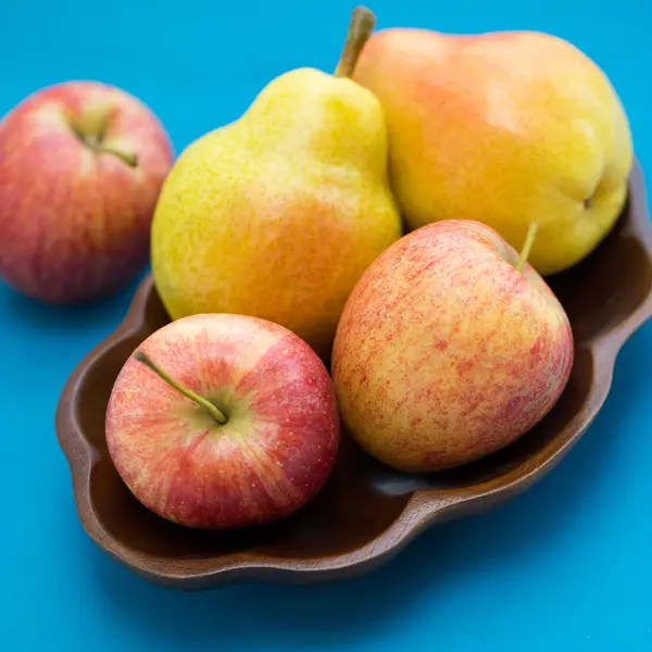 Peras y manzanas en un tazón de madera —  Fotos de Stock