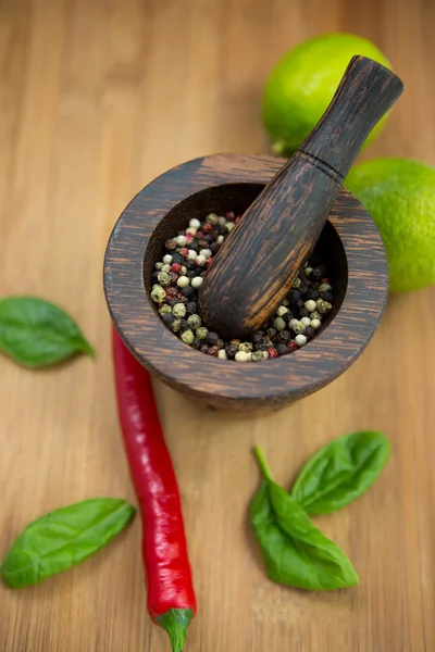 Red Hot Chili Peppers, lime and spices with Mortar and Pestle over wooden background — Stock Photo, Image