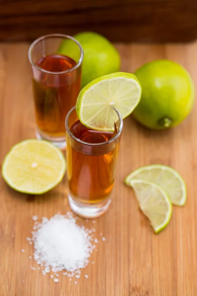 Tequila, limão e sal sobre mesa de madeira Imagens De Bancos De Imagens