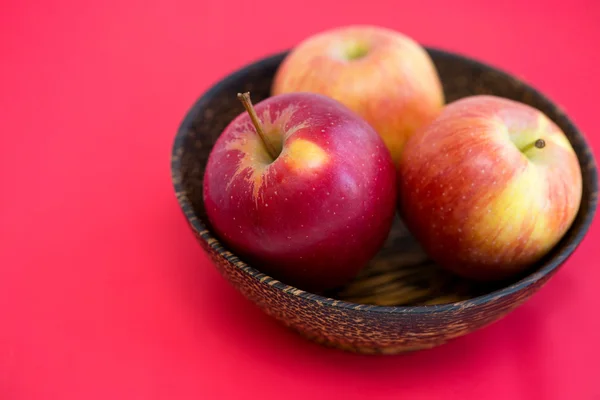 Cuenco de madera con manzanas sobre fondo rojo —  Fotos de Stock