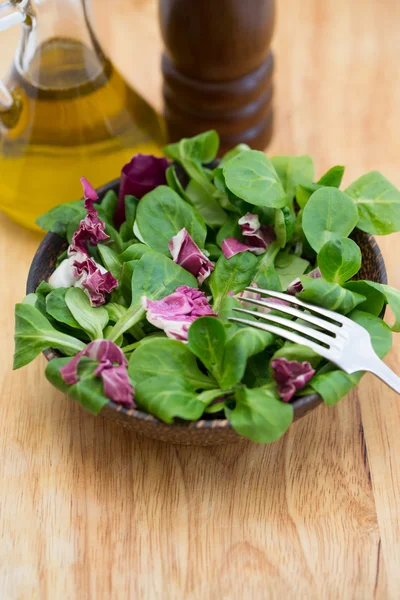 Wooden bowl with corn salad leaves and radicchio — Stock Photo, Image