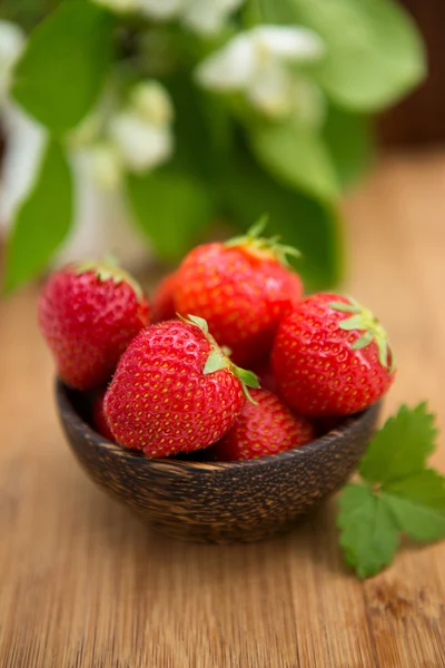 Färska jordgubbar i en trä skål på en trä bakgrund — Stockfoto