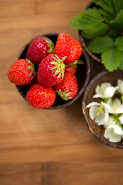 Fresh strawberries in a wooden bowl on a wooden background — Stock Photo, Image