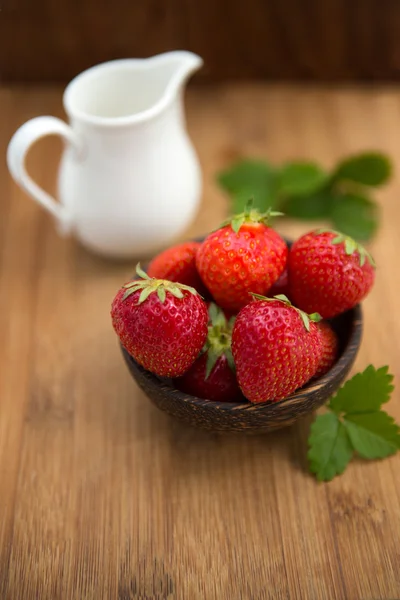 Färska jordgubbar, mjölk på trä bakgrund — Stockfoto