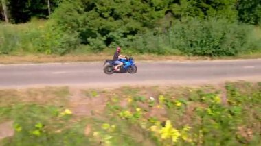 Genç bir adam şehir dışında motosiklet sürüyor. İHA