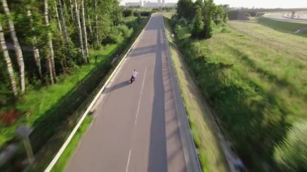 Un jeune homme conduit une moto à l'extérieur de la ville. Un drone — Video