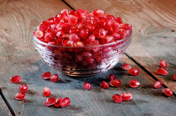 Pomegranate seeds on an old wodden board — Stock Photo, Image