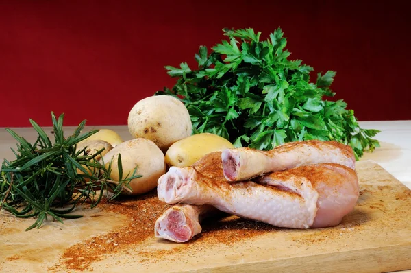 Chicken thighs and potatoes on a cutting board — Stock Photo, Image