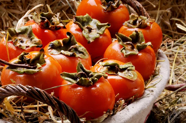 Wicker basket full of persimmons — Stock Photo, Image