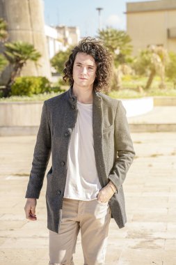 Yakışıklı genç adam sokakta gülümsüyor.