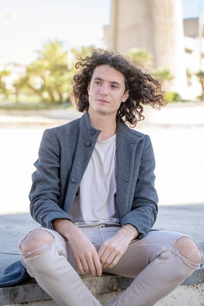 Junger Mann Mit Langen Haaren Sitzt Auf Dem Bürgersteig Auf — Stockfoto