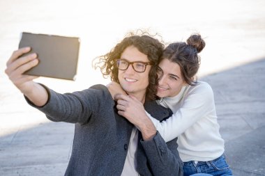 Genç turistler gülümsüyor ve şehirde selfie çekiyor.