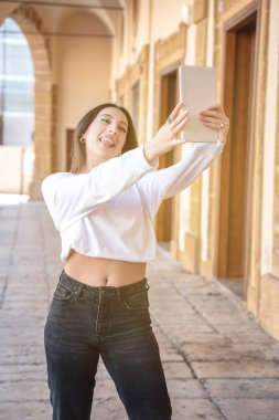 Tablet tutamağı olan, teknoloji, kibir ve sosyal ağ kavramları ile selfie çeken genç, güzel İtalyan bir kadın.