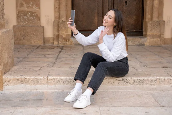 若い笑顔の女性が携帯電話の屋外でデートビデオ通話をします — ストック写真